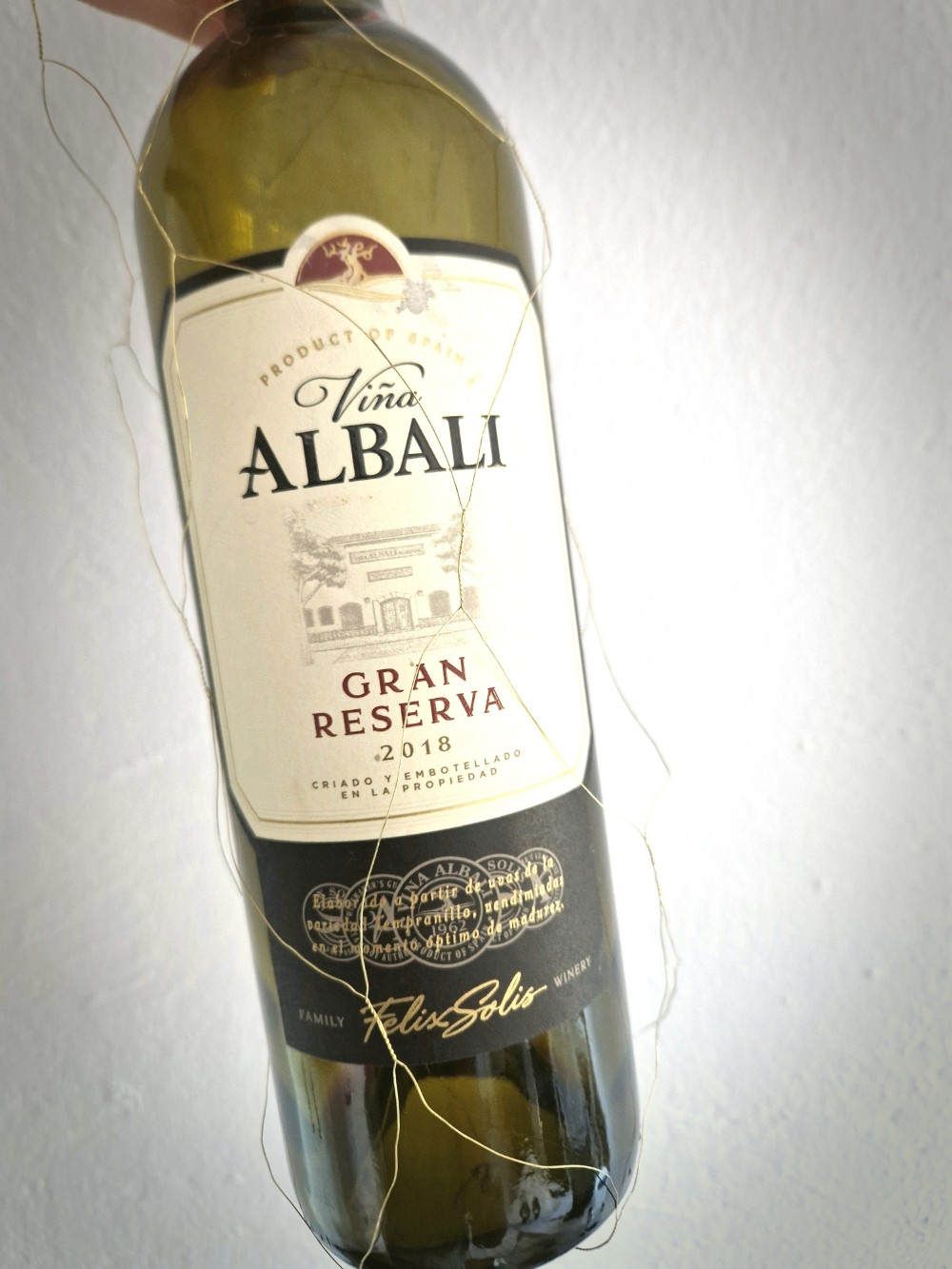 Eine Flasche Rotwein vor weißer Tapete