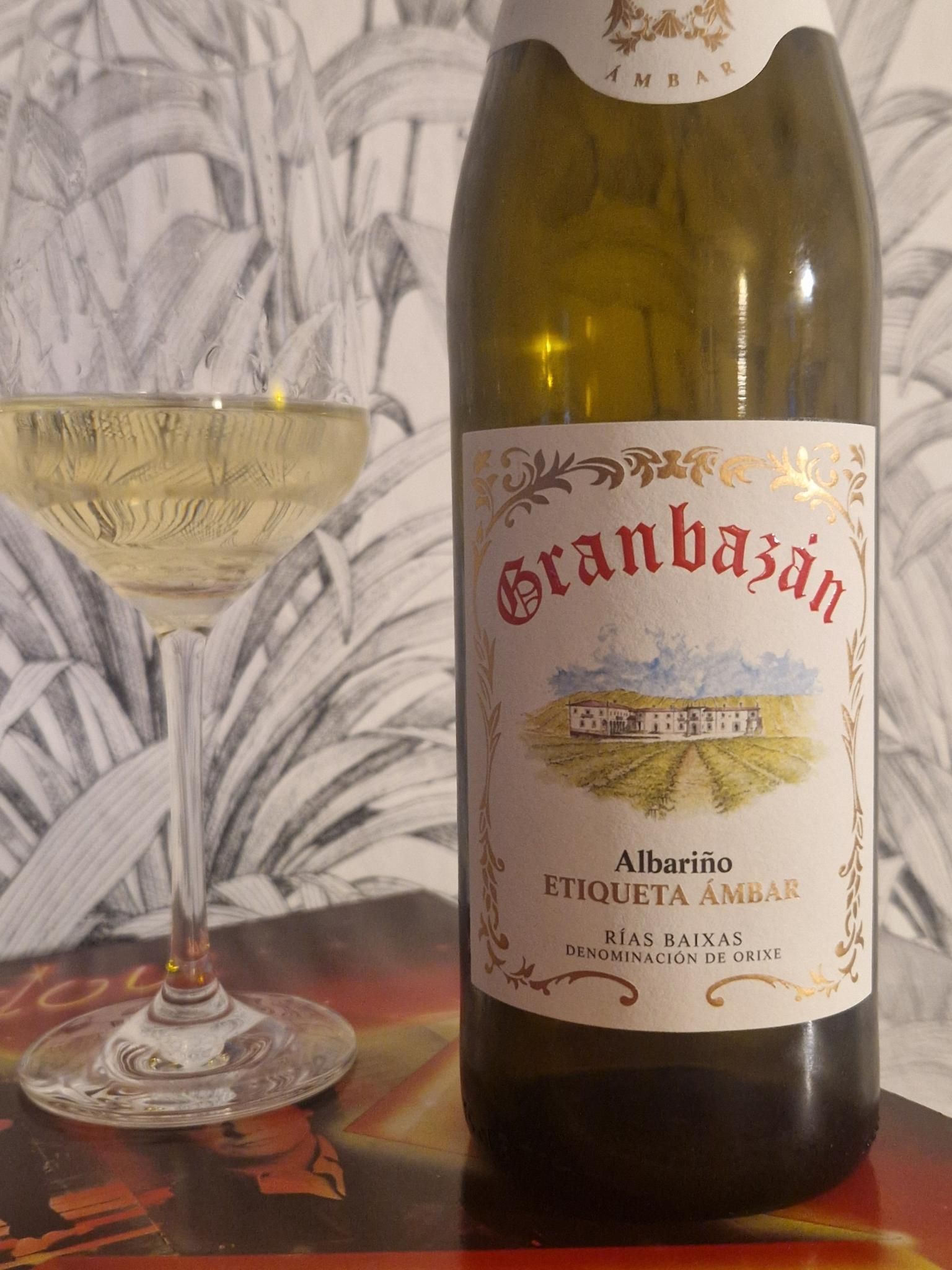 Eine Glas Weißwein neben einer geöffneten Flasche