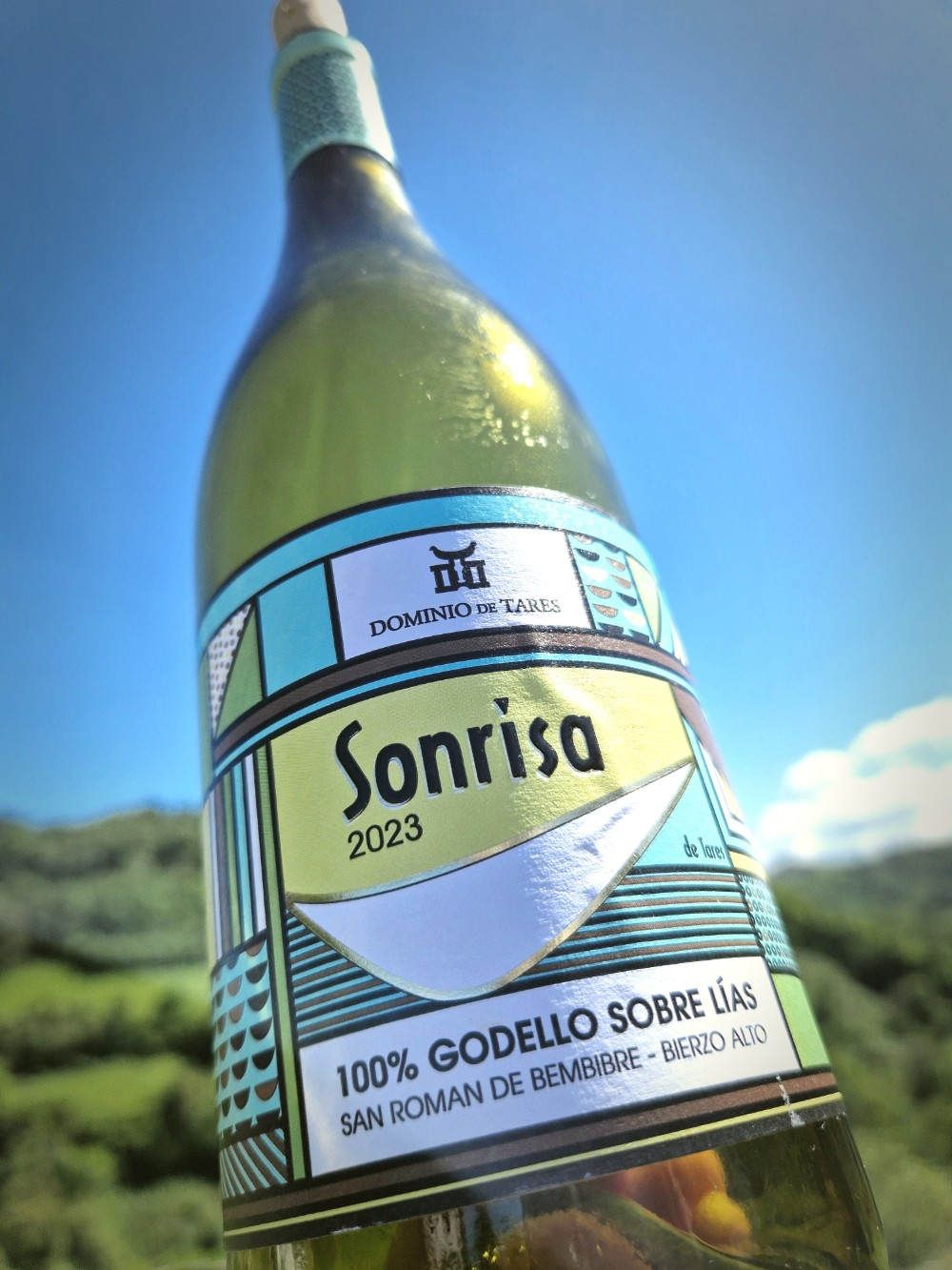 eine Flasche Wein vor einem grünen Hügel