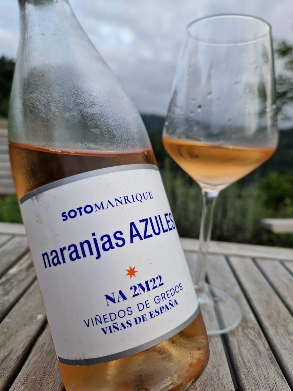 Eine Flasche Roséwein auf der Terrasse mit einem Glas im Hintergrund