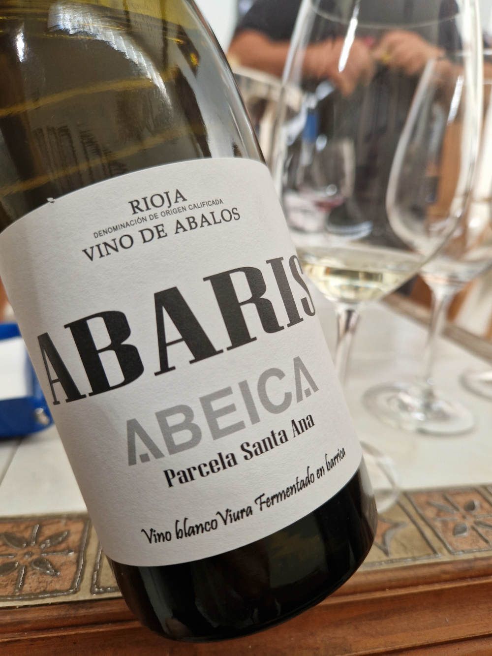 eine Flasche Weißwein vor einem Verkostungstisch