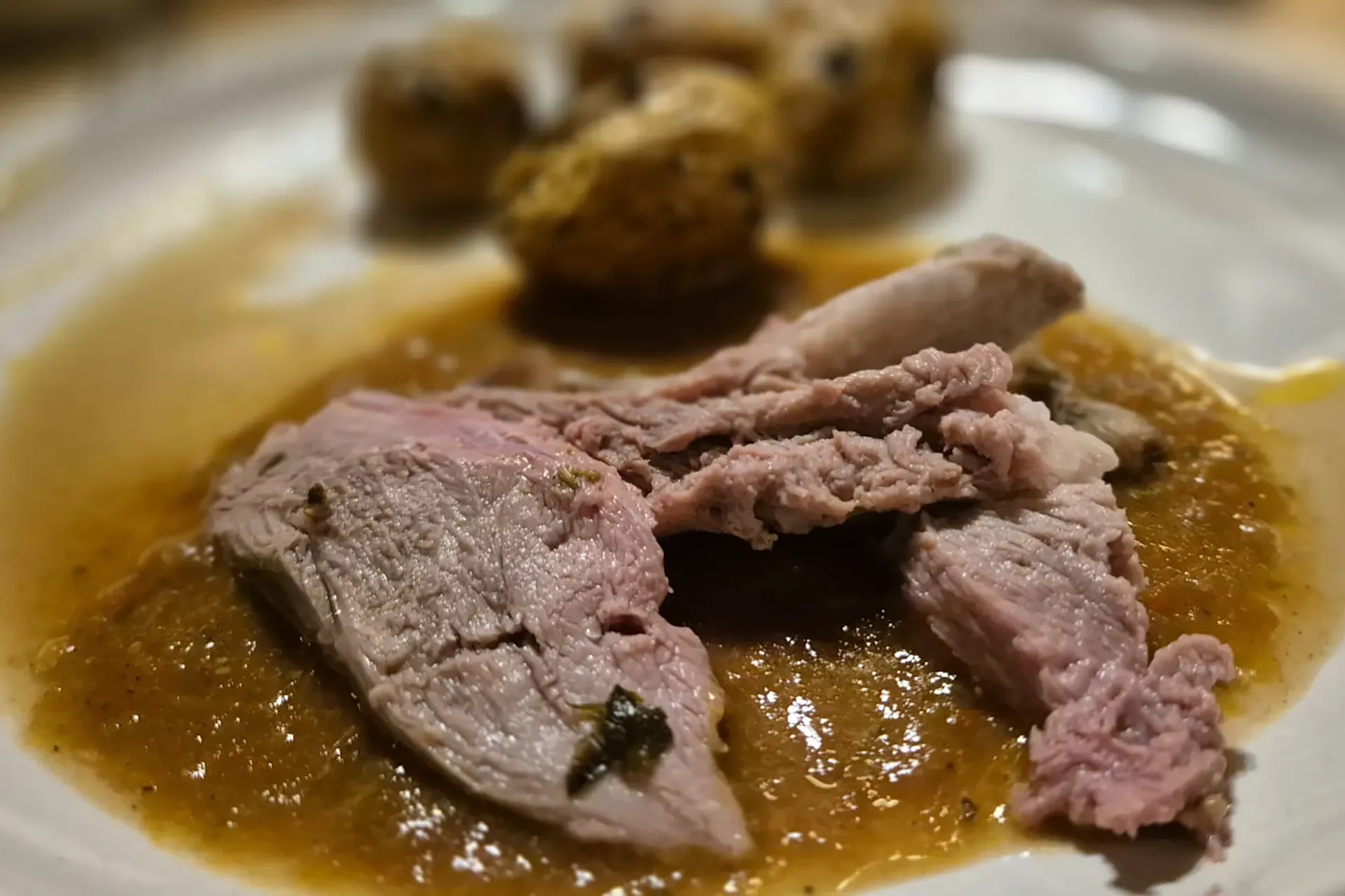 Ein Teller mit einem Braten Kartoffeln und Sauce
