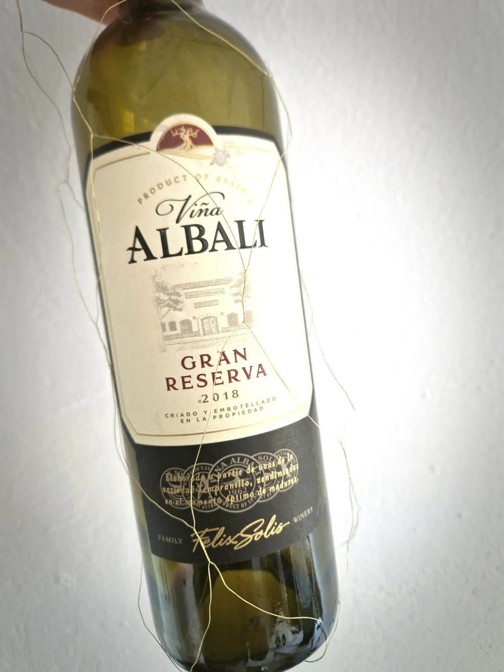 Eine Flasche Rotwein vor weißer Tapete