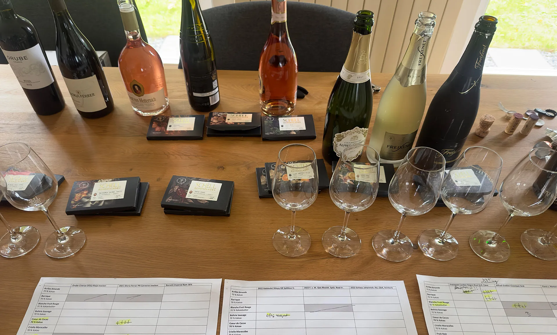 Tisch mit vielen Gläsern, Weinflaschen und Schokoladentafeln