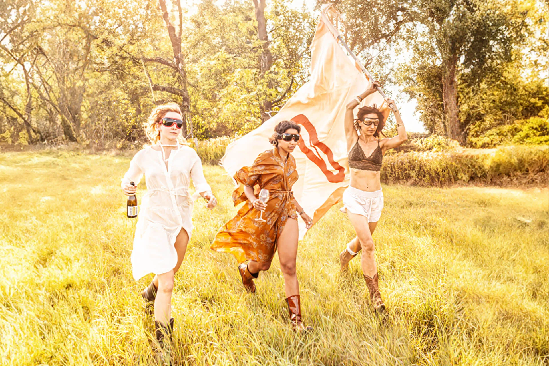 drei junge Frauen laufen über eine sonnendurchschienene Wiese