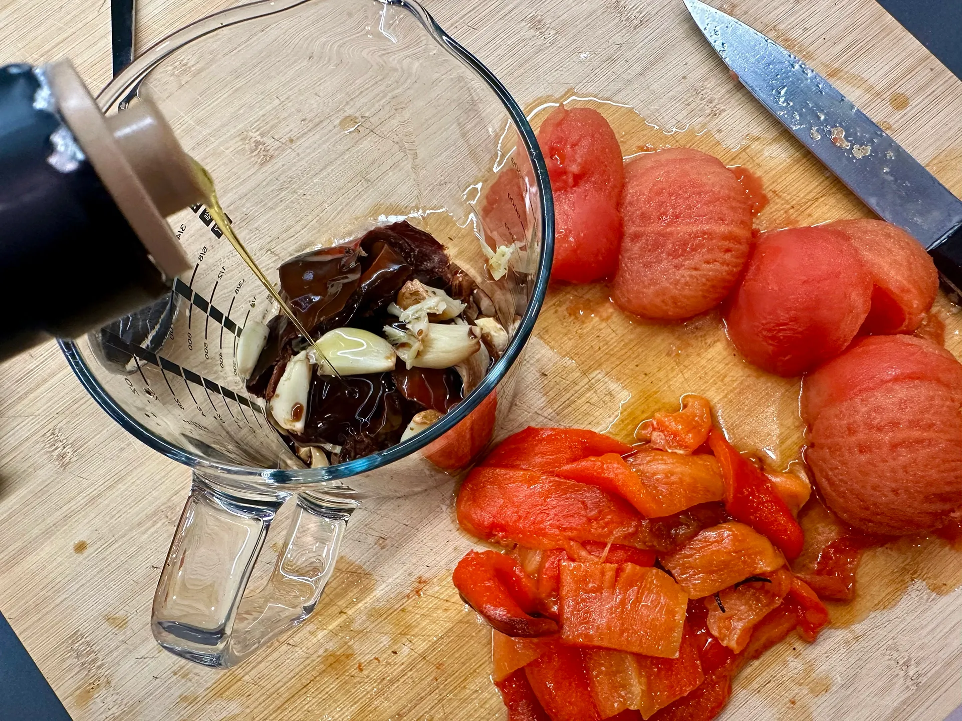 Glasbehälter und Olivenöl läuft rein, Paprika, Tomate, Knoblauch, Ñora