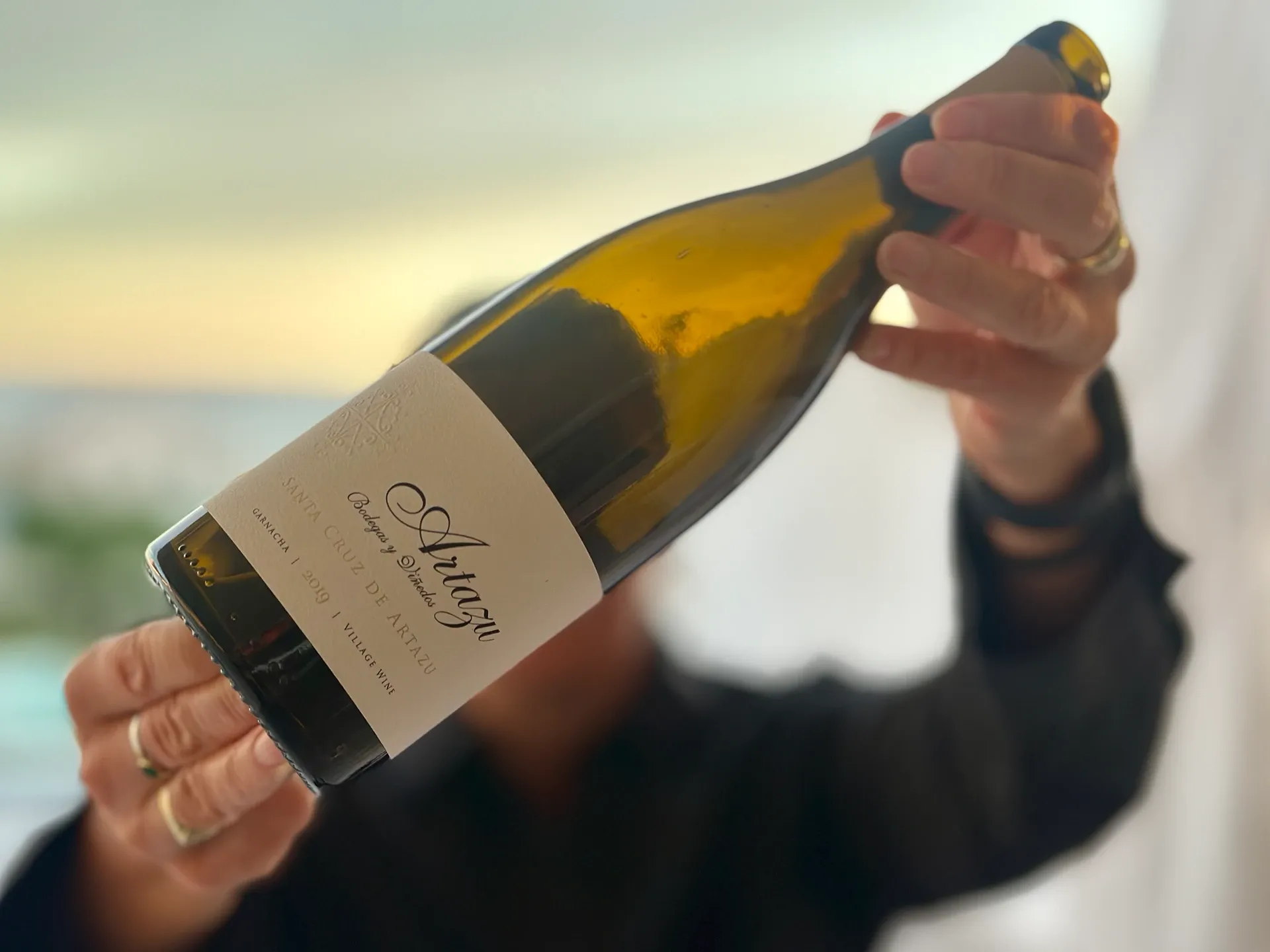 eine Frau hält eine Weinflasche hoch vor das Gesicht