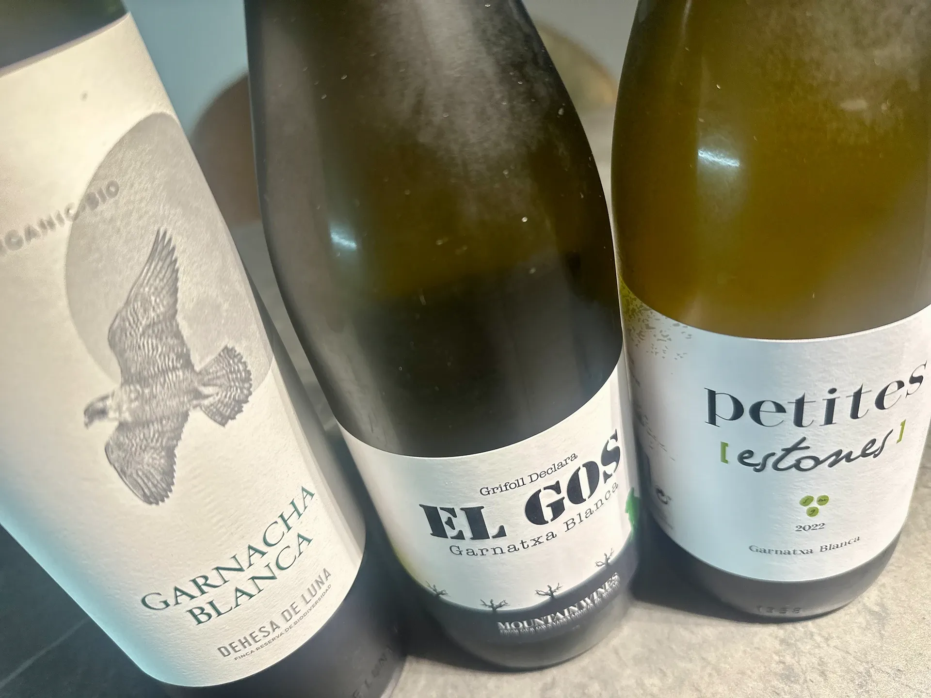 drei Weissweinflaschen stehen auf einem Tisch