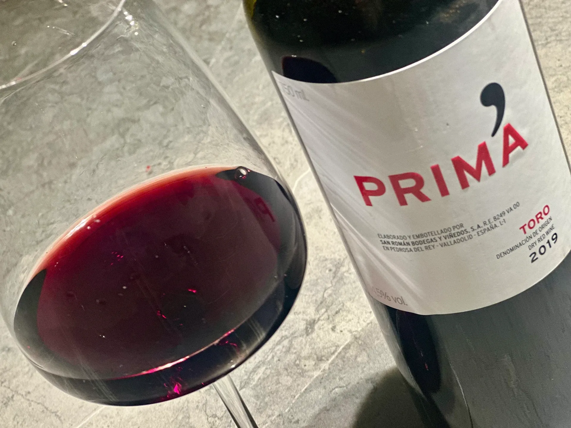 Flasche Rotwein mit Aufschrift Prima und Glas daneben