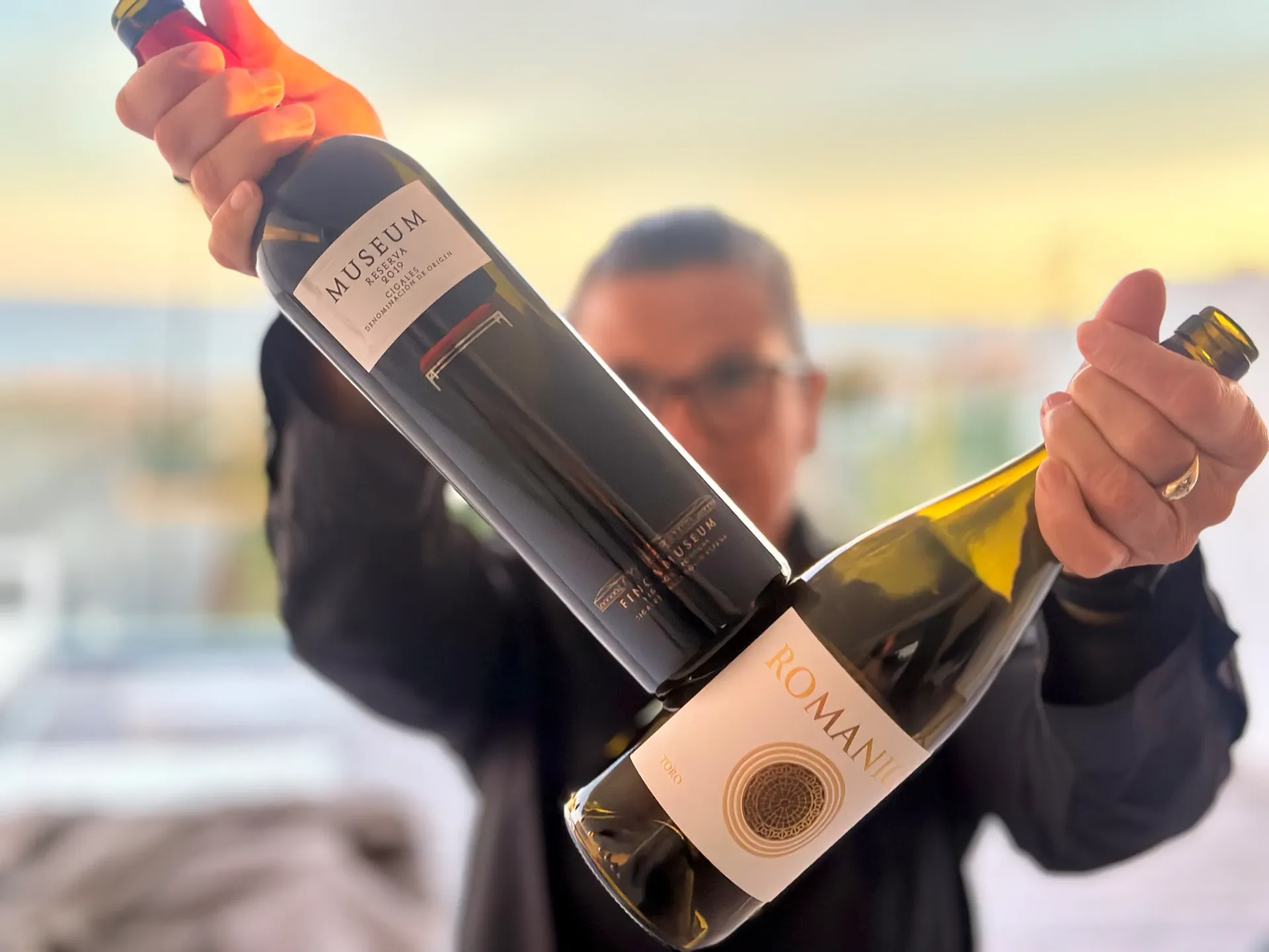 Frau hält zwei Weinflaschen in die Kamera