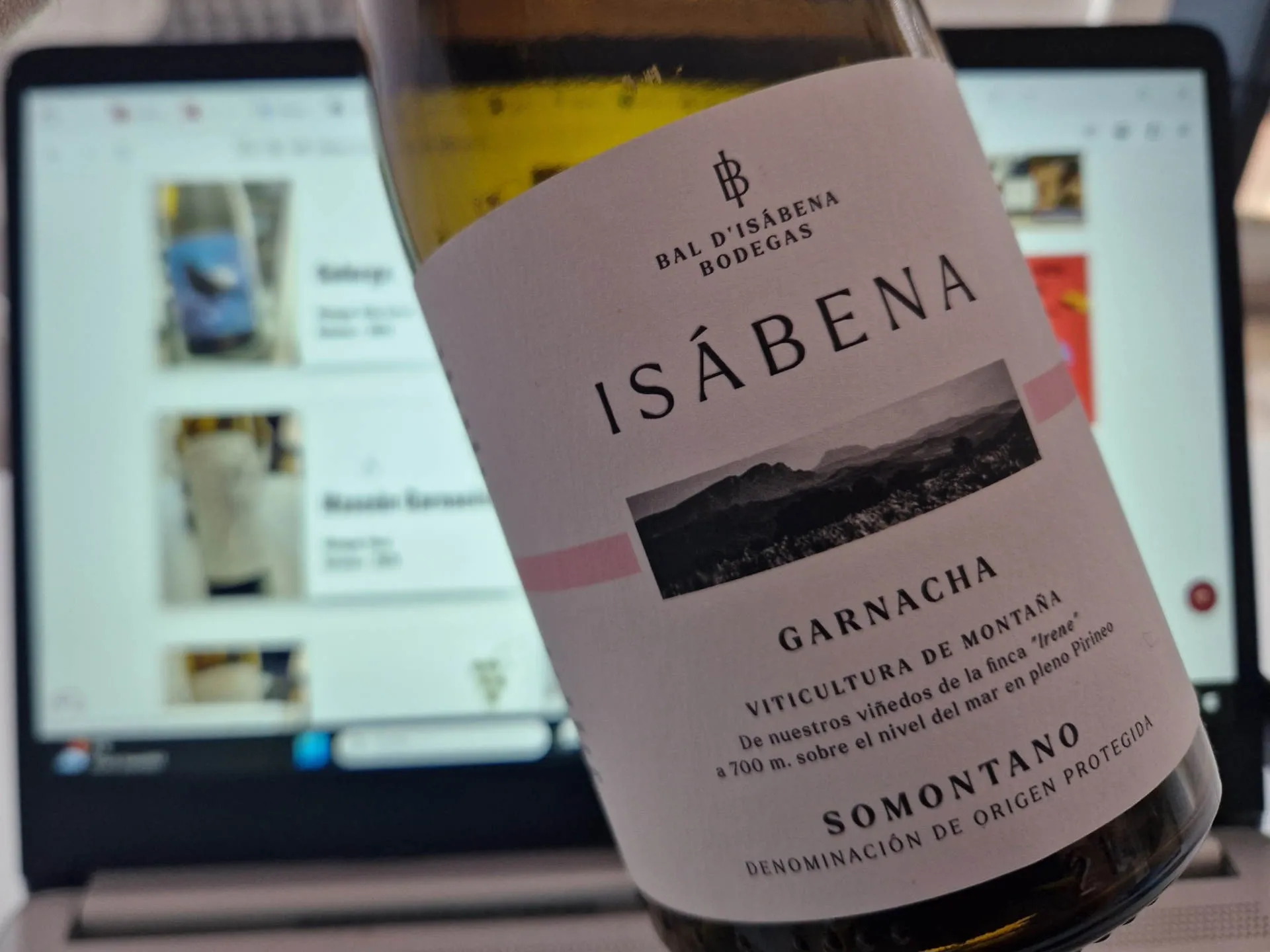 Eine Flasche Wein wird vor einen Computerbildschirm gehalten.