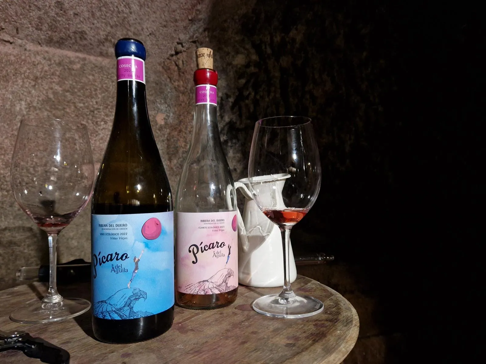 Zwei Weinflaschen mit Gläsern auf einem Holzfass