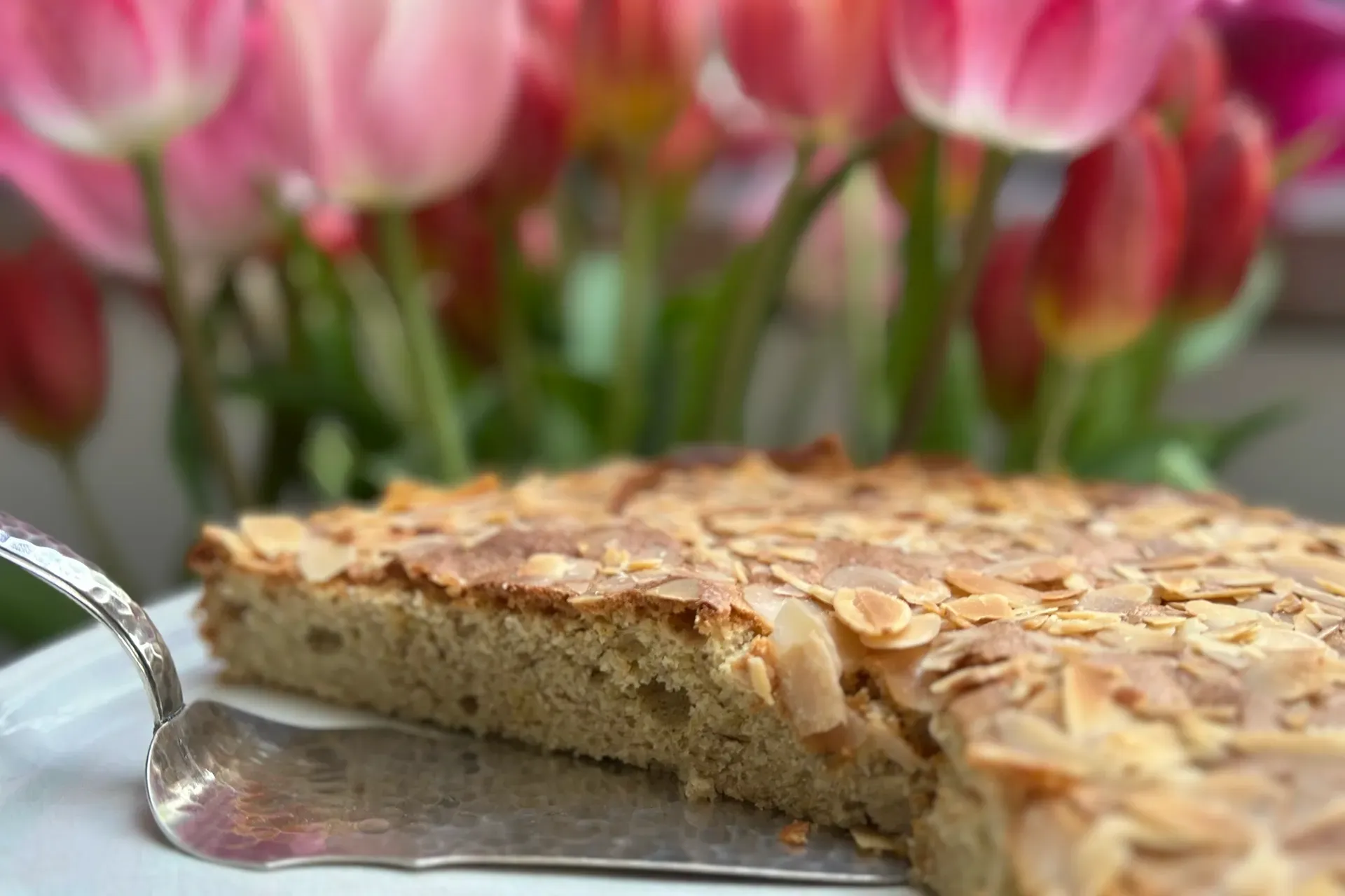 Kuchen auf Platte mit Tulpen im Hintergrund