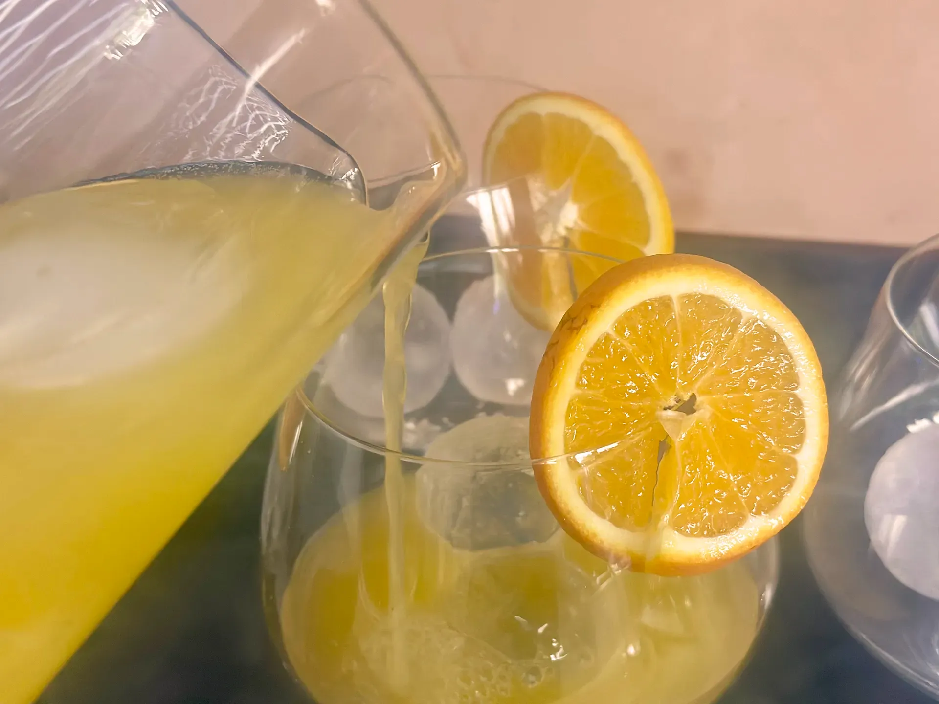 Karaffe und grosses Glas, Orangensaft wird eingeschenkt