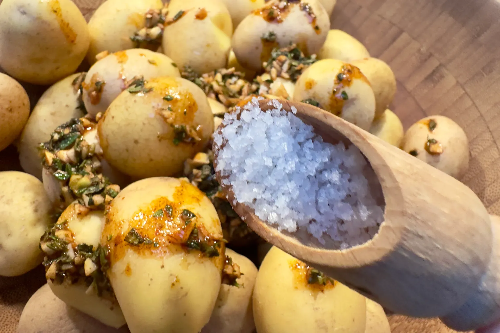 Kartoffeln in einer Schale und ein großer Holzlöffel mit Meersalz