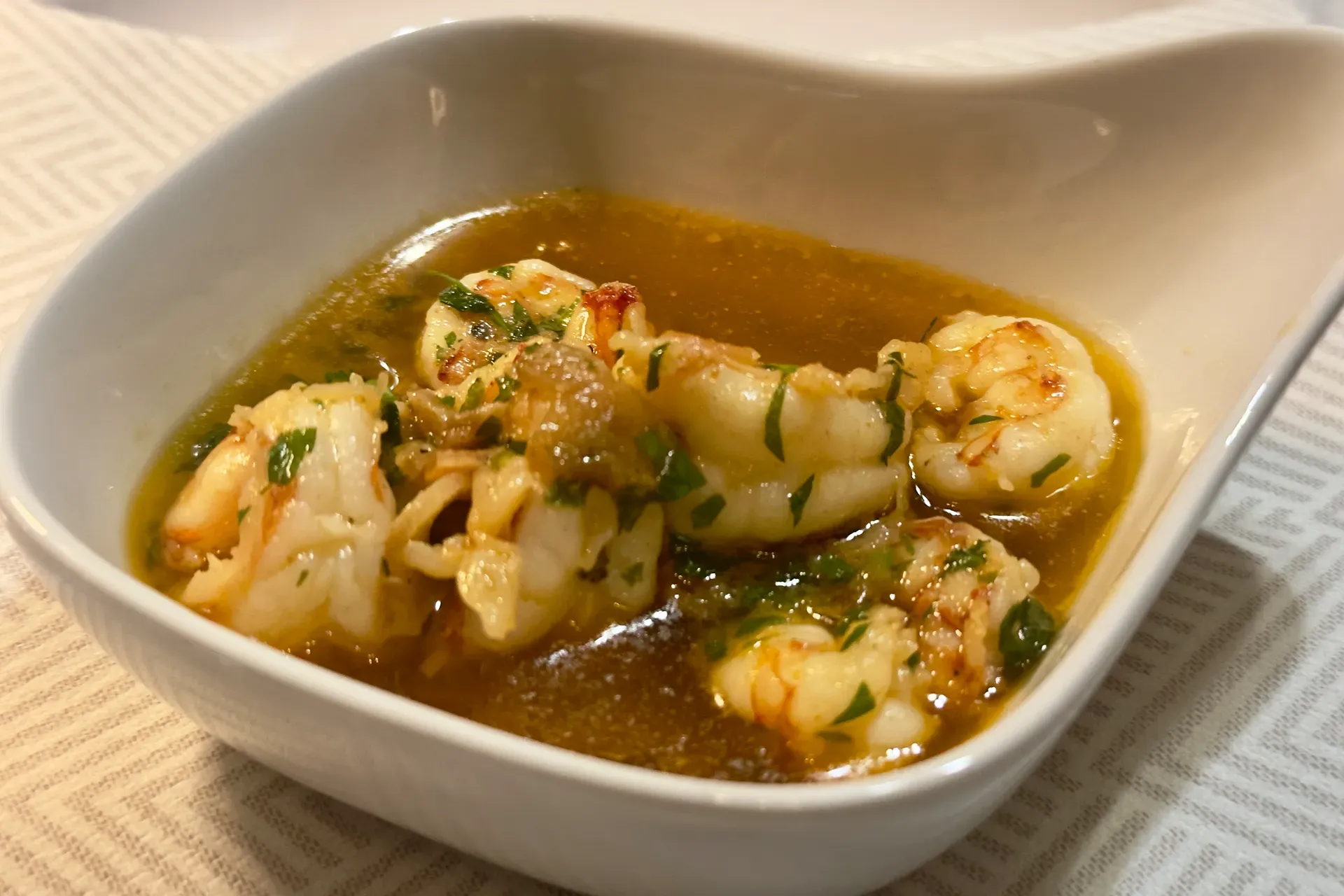 Ein weißes Tonförmchen mit Knoblauchgarnelen