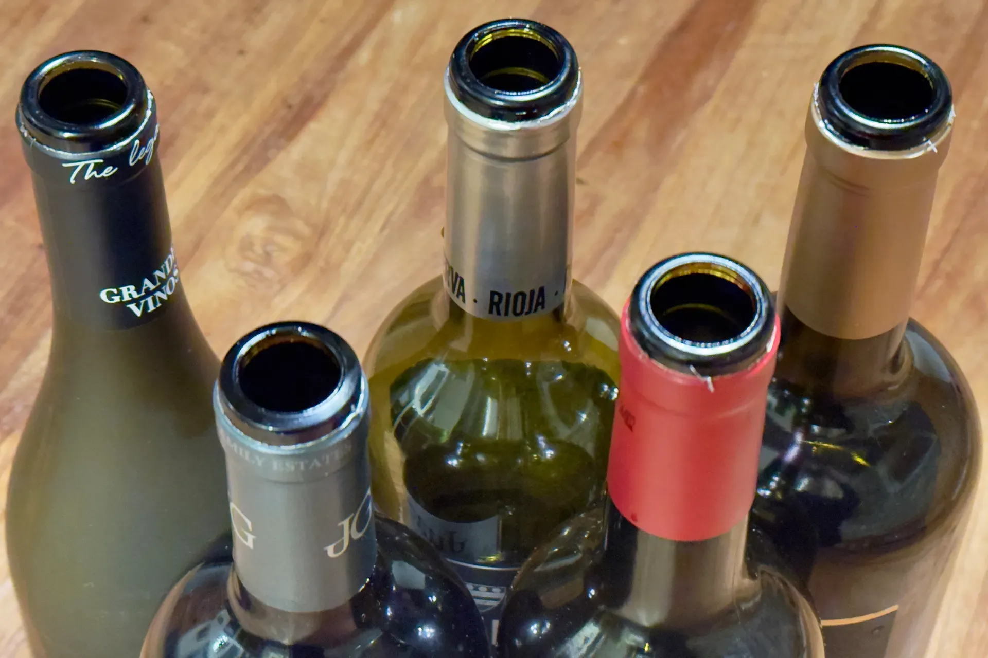 Fünf Weinflaschen von oben mit den Öffnungen