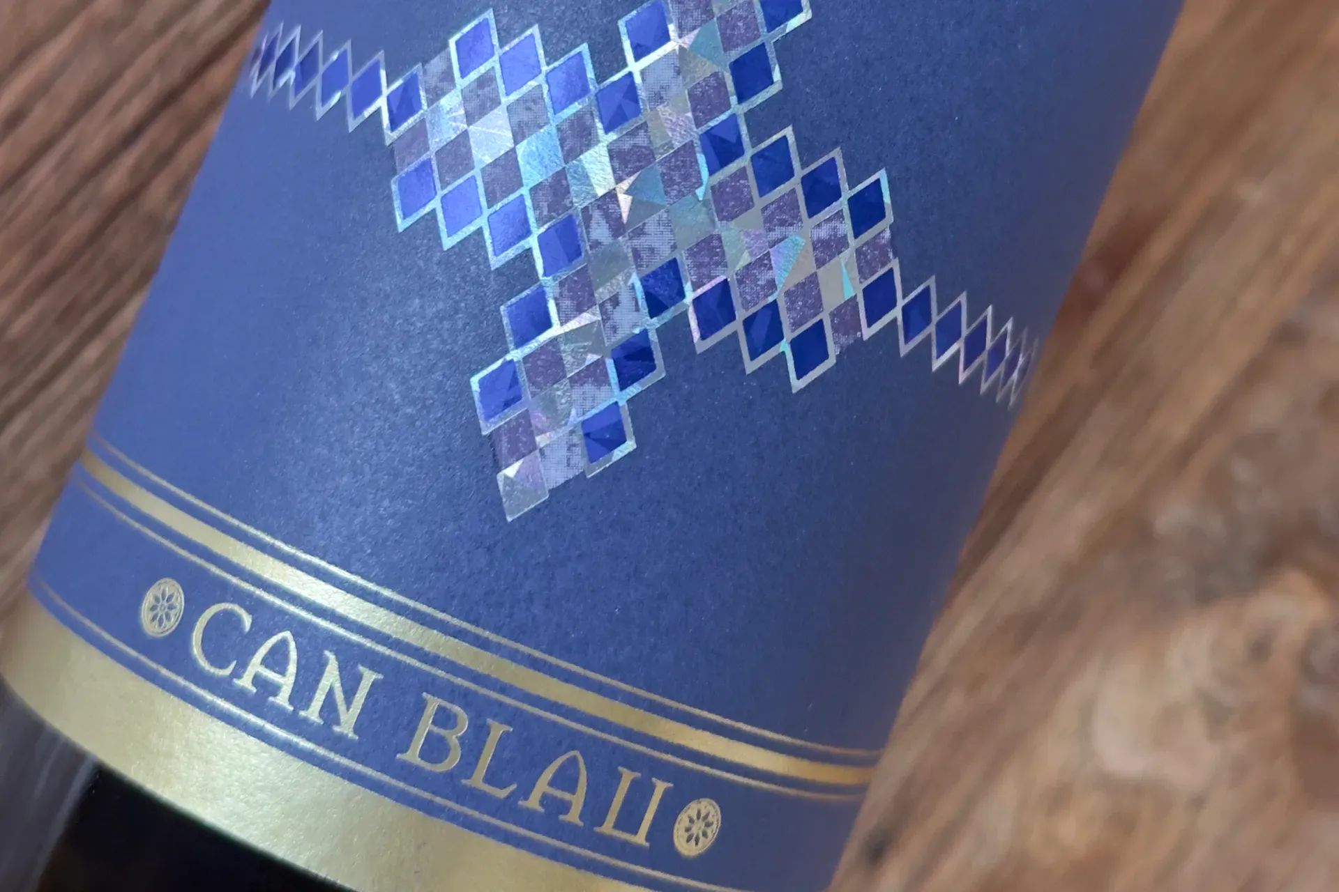 Weinfalsche liegt auf Holztisch mit Etikett von Can Blau