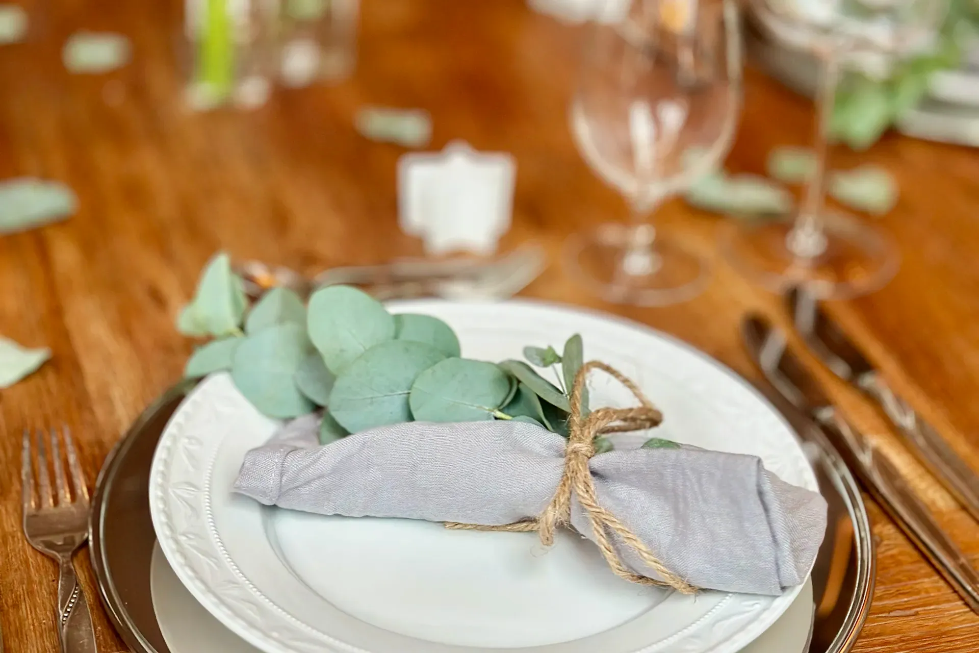 festlich gedeckter Tisch mit weissem Geschirr und Eukalyptus