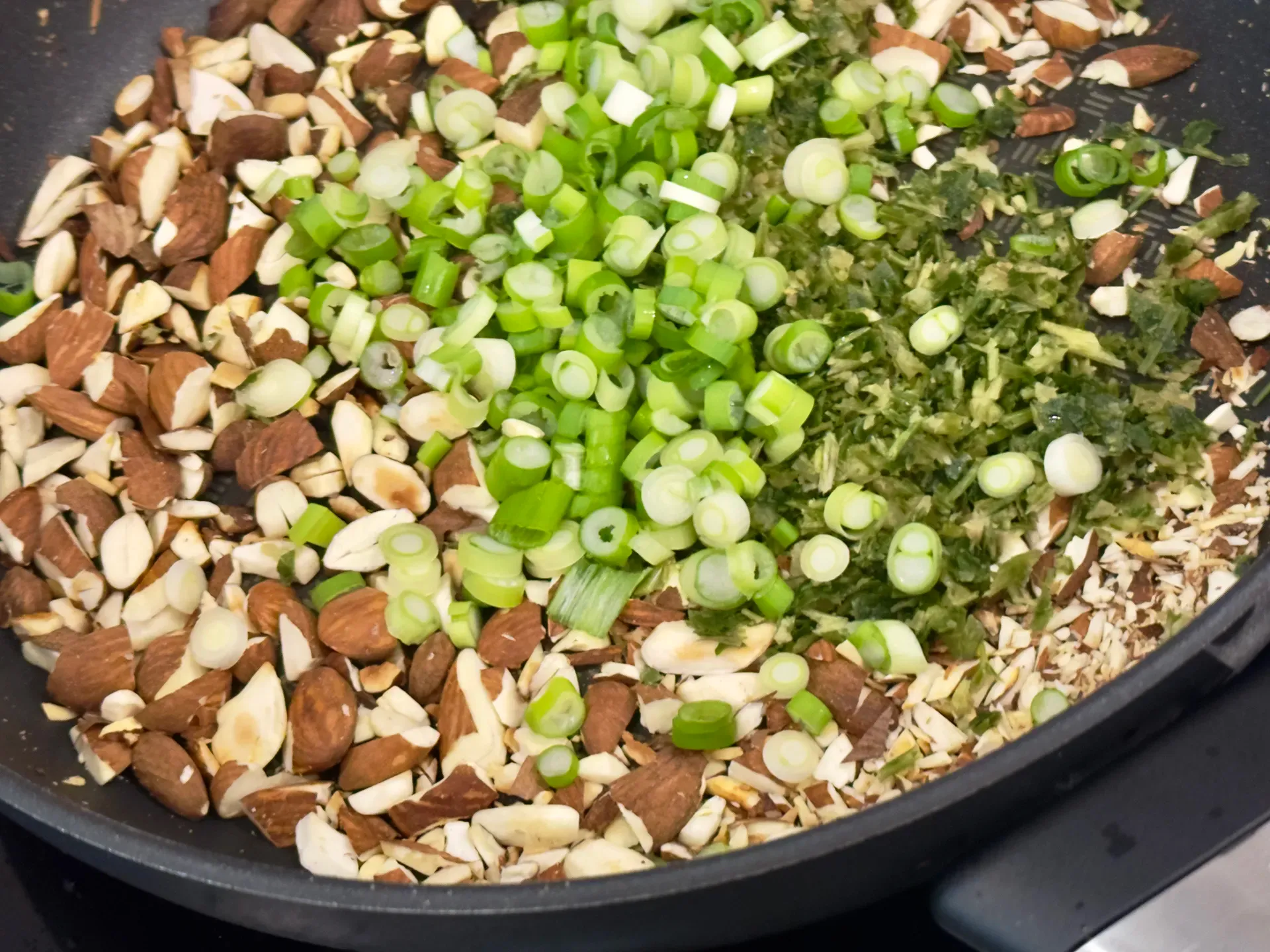 Mandlen, Zwiebeln und Kräuter in einer Pfanne