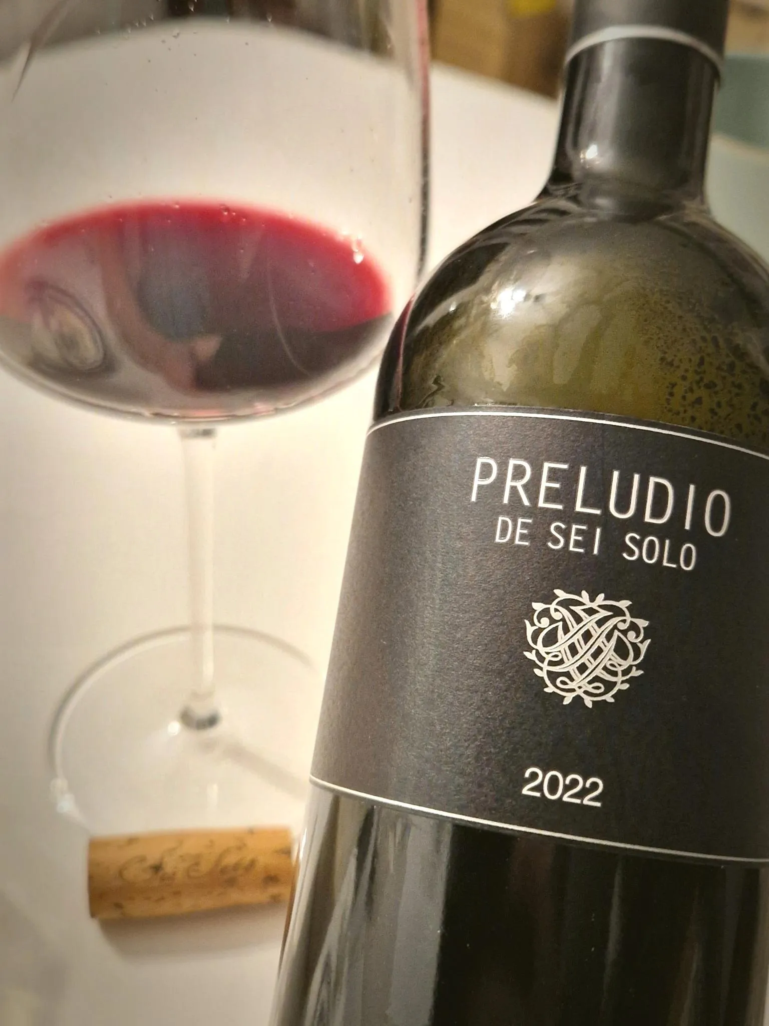 Eine leere Flasche Rotwein vor einem noch halb gefüllten Glas.