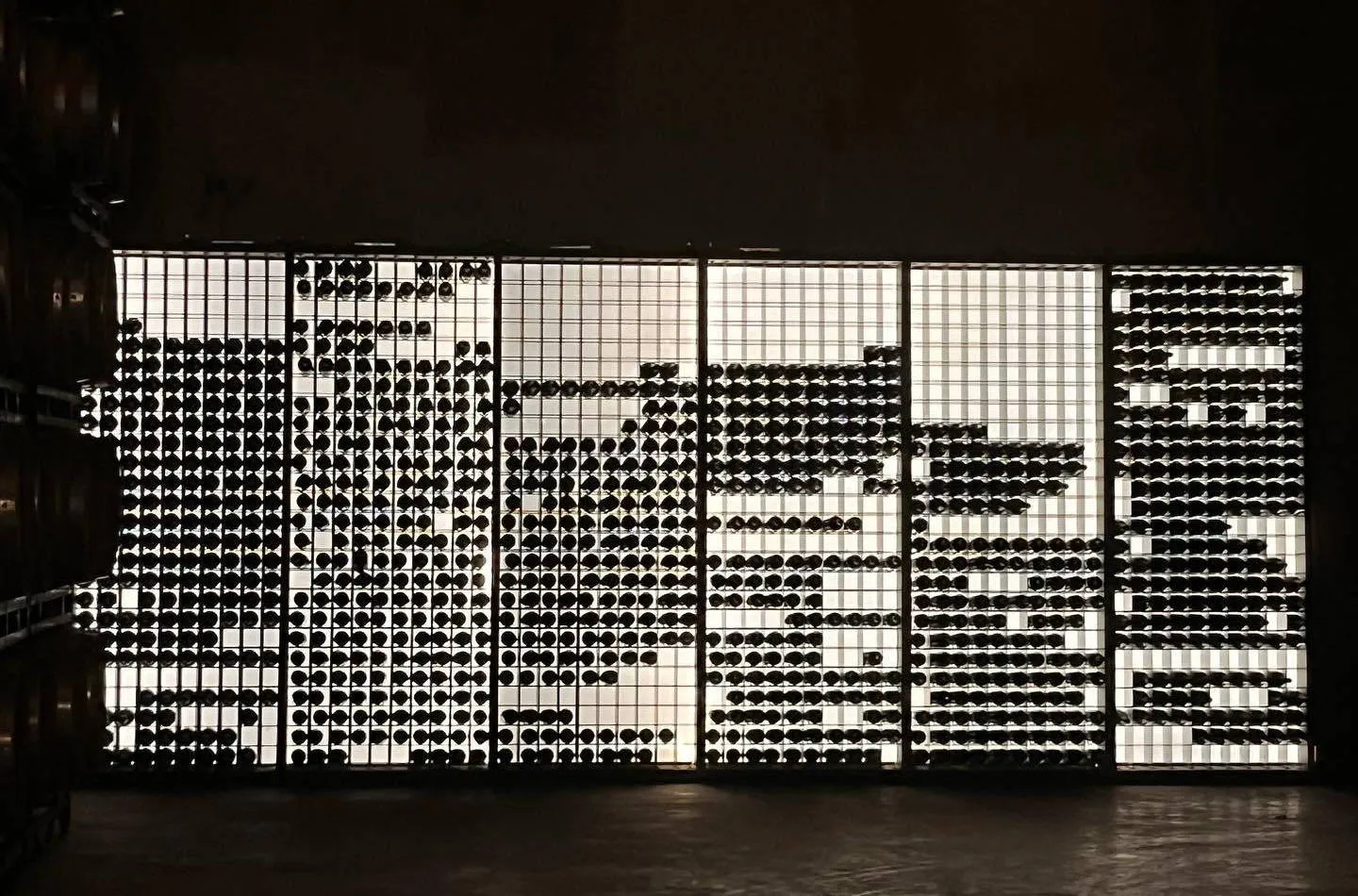 Eine beleuchtete Wand mit Weinflaschen beim Weingut Pago Aylés