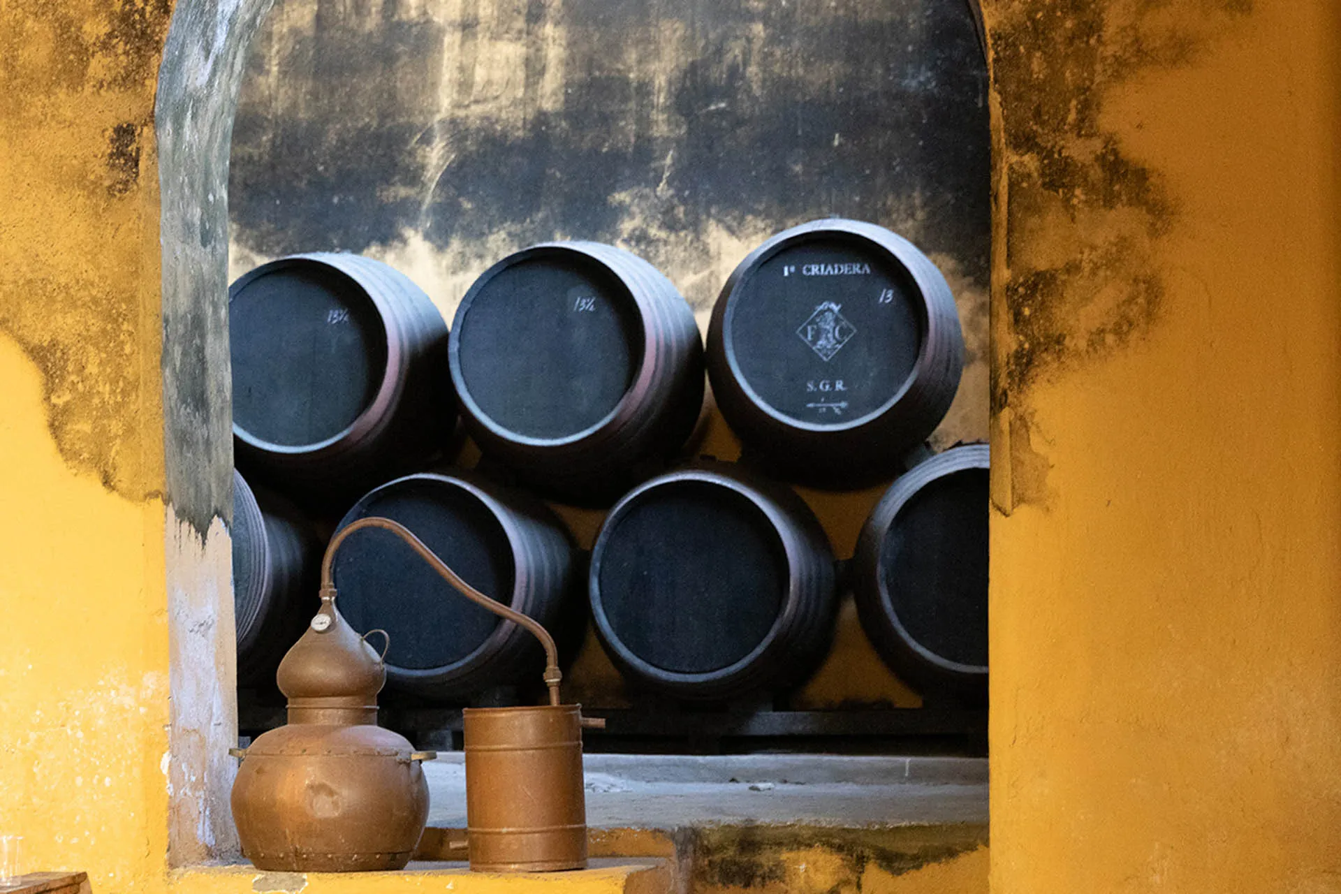 Sherryfässer in einer Bodega mit alten Geräten davor