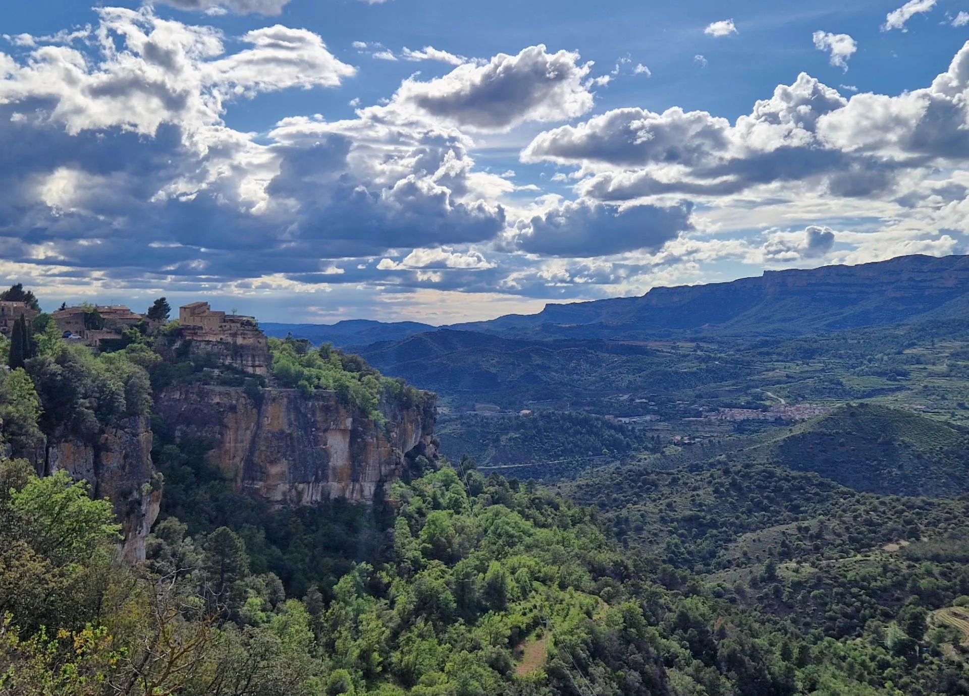 ein Dorf auf einem Hügel, im Hintergrund Berge