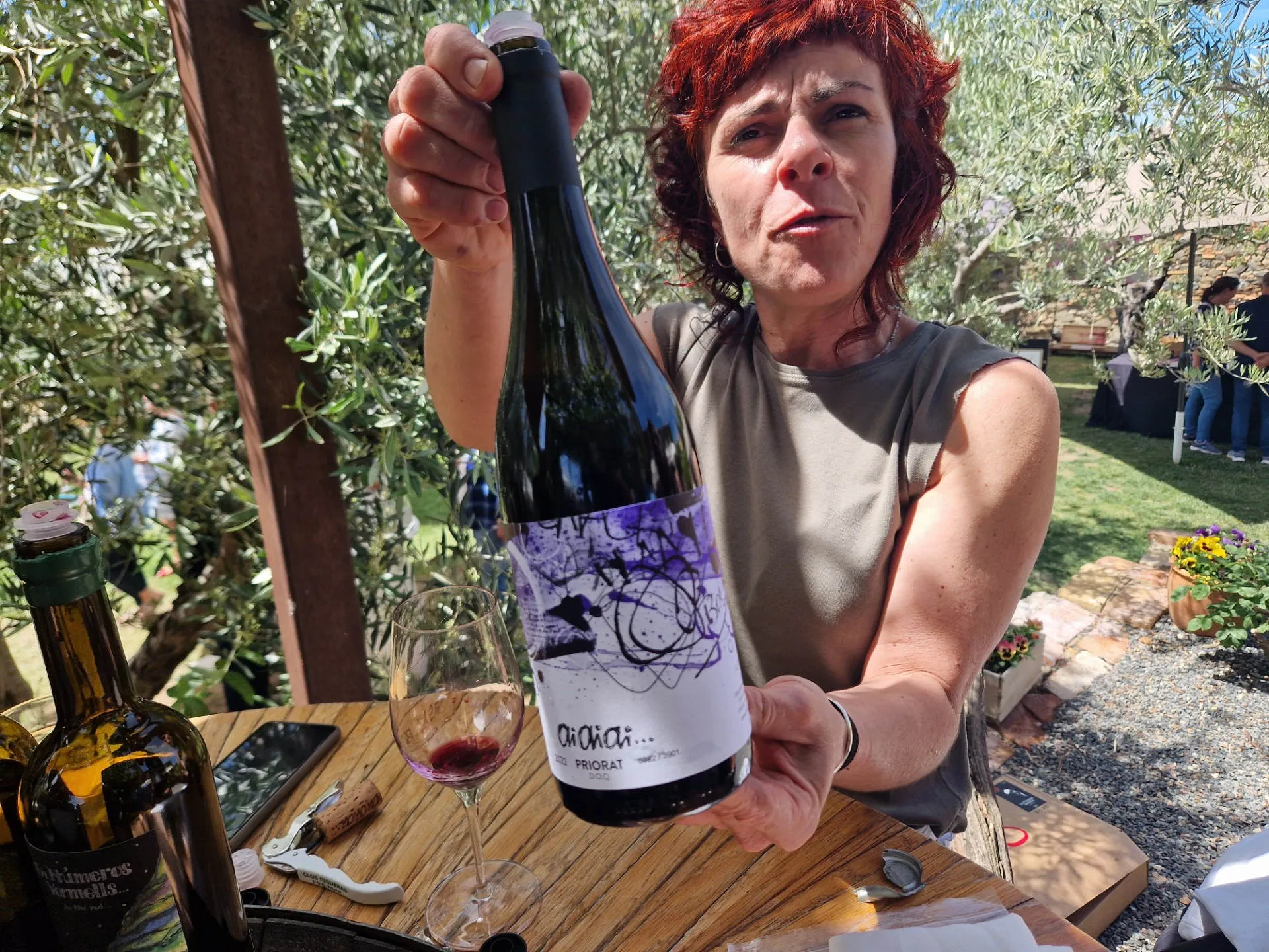 EIne Frau hält eine Flasche Wein in die Kamera