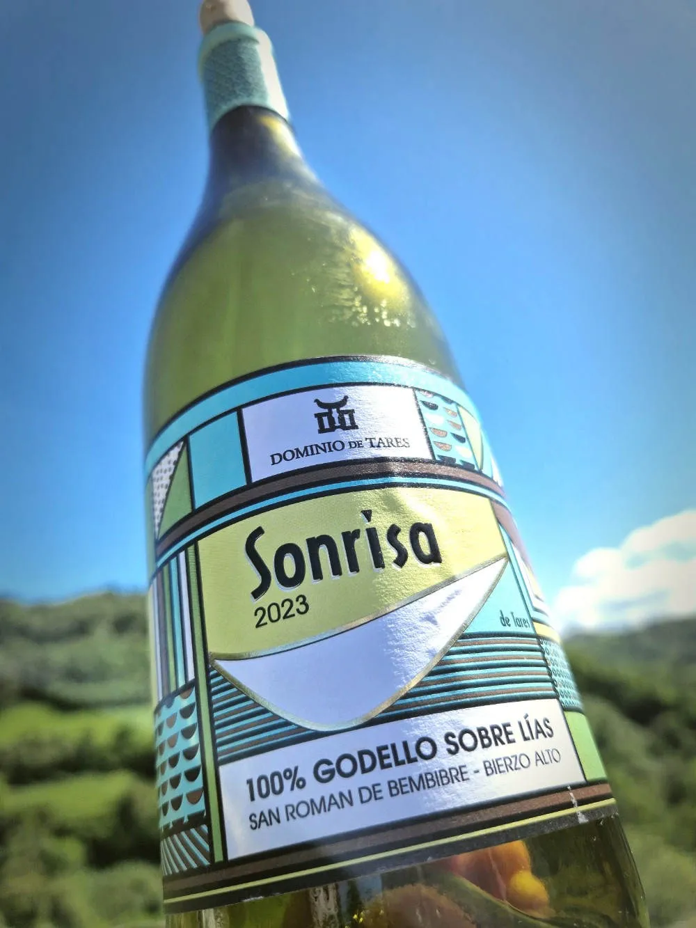 eine Flasche Wein vor einem grünen Hügel