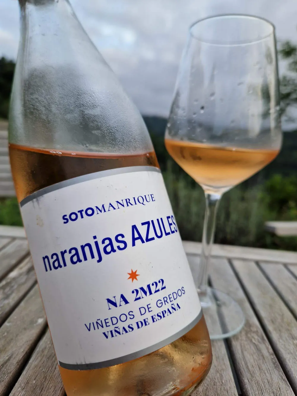 Eine Flasche Roséwein auf der Terrasse mit einem Glas im Hintergrund