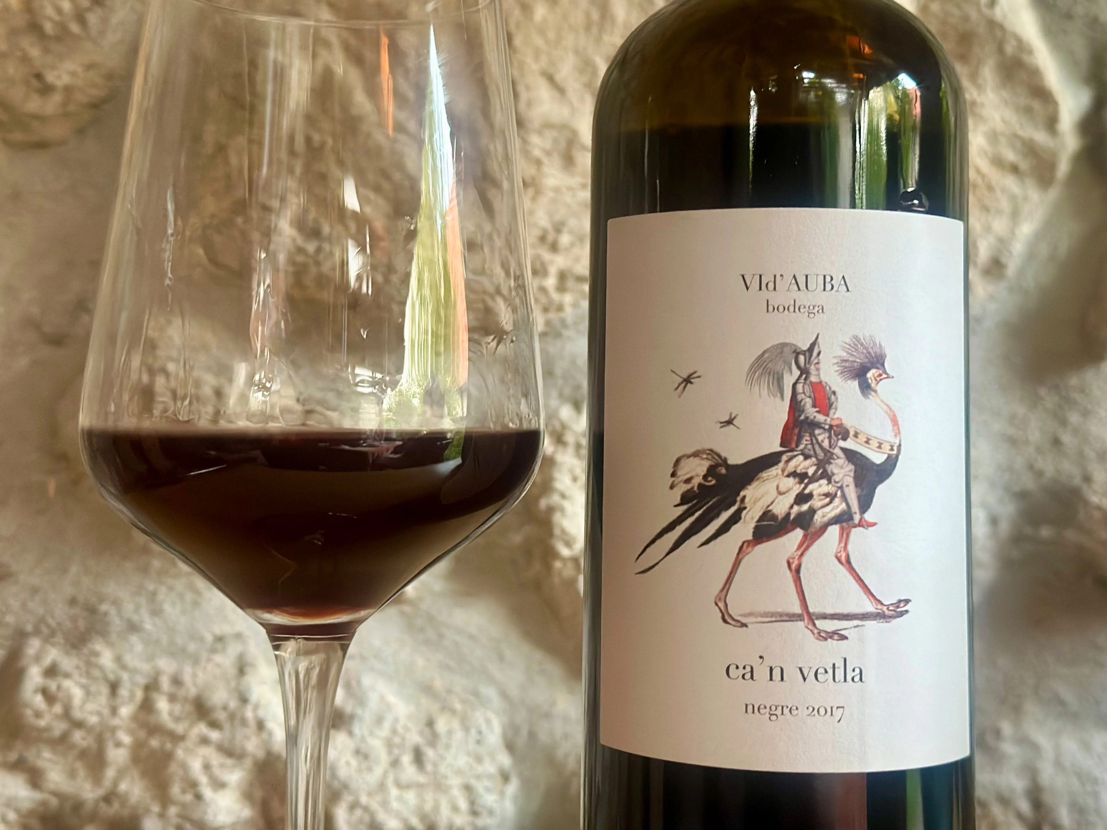 Rotweinflasche mit Glas auf Etikett ein Vogestrauss mit einem Reiter