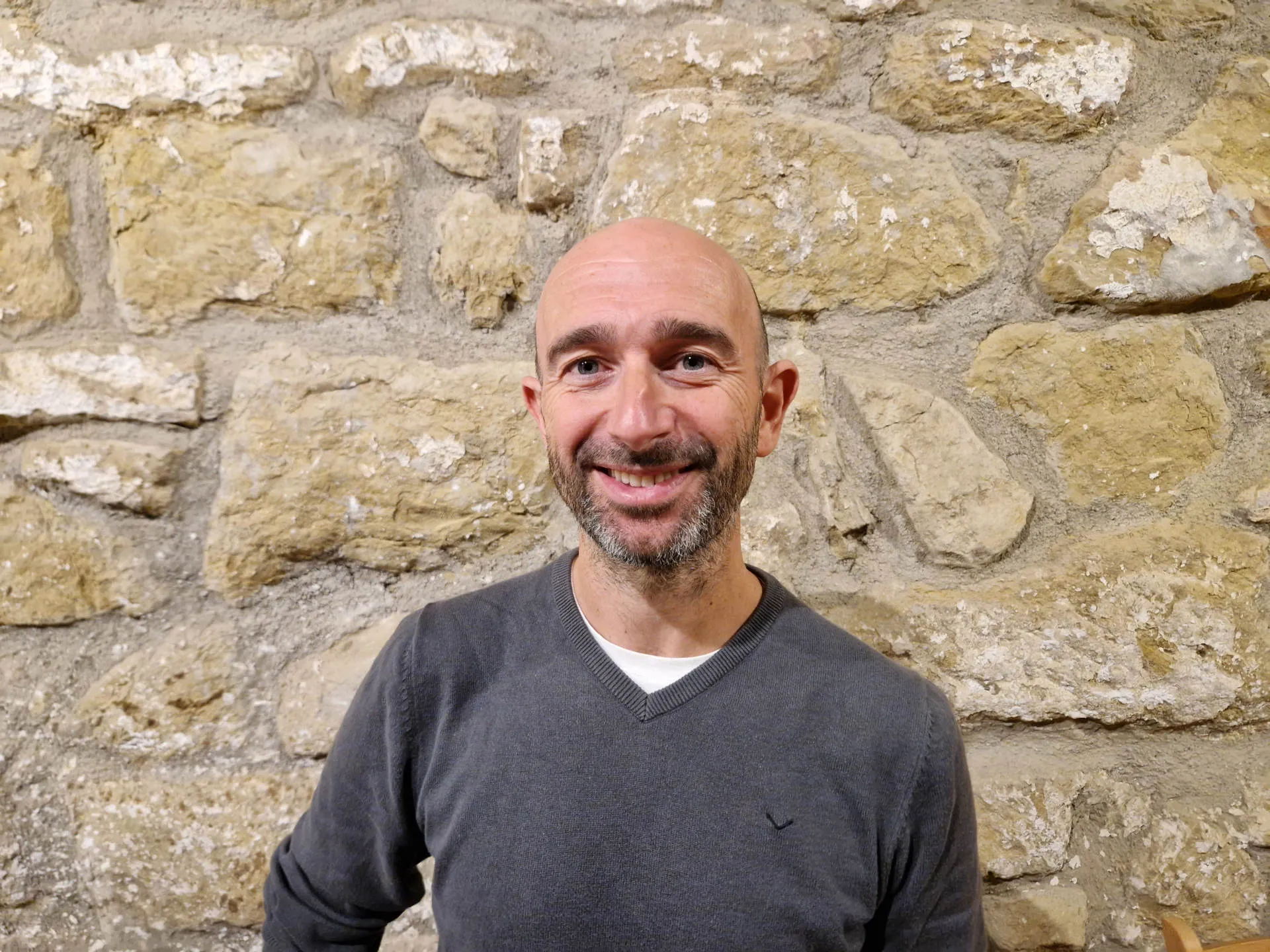 Ein lächelnder Mann vor einer Steinmauer