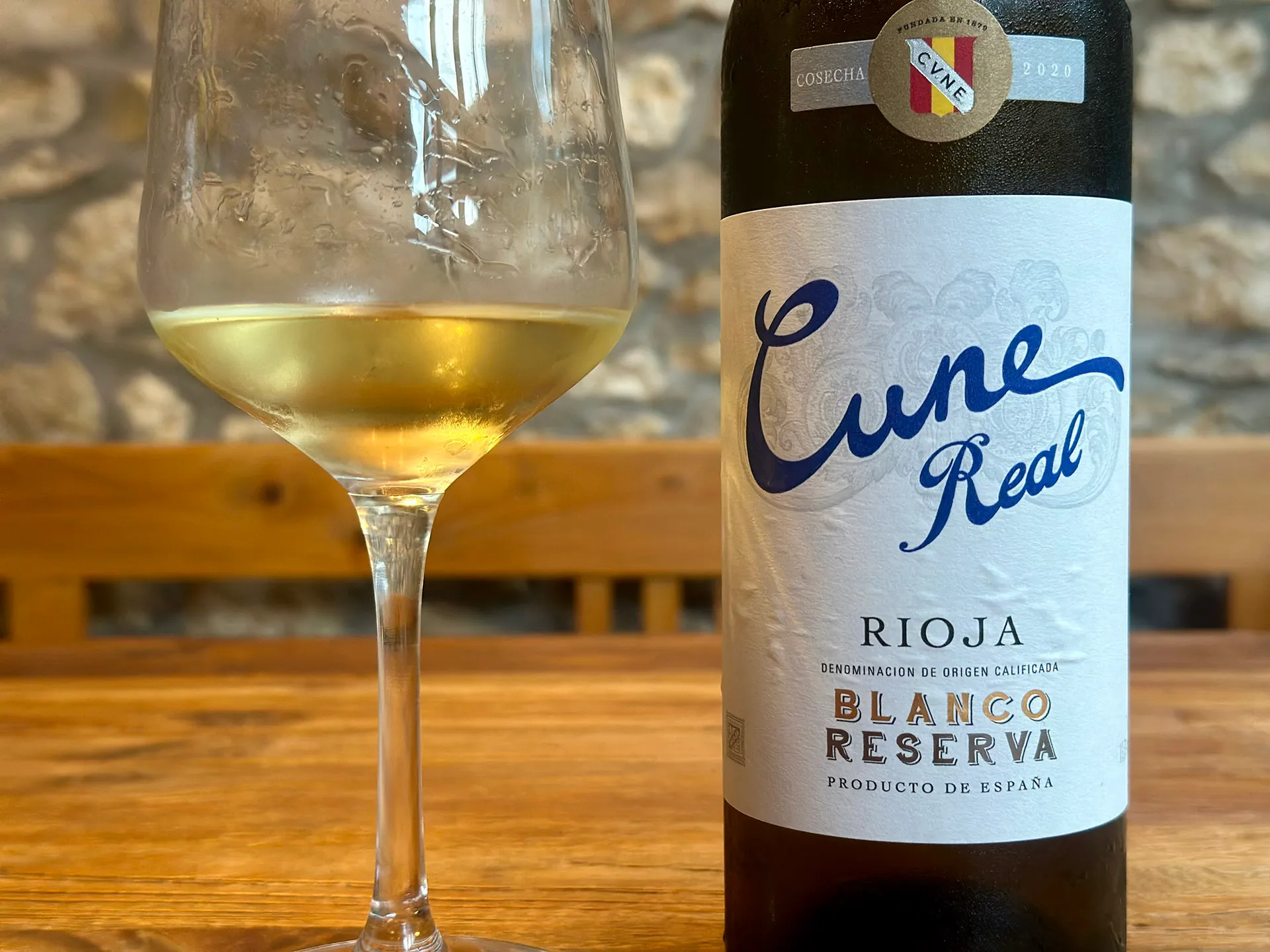 Weinflasche mit Schriftzug Cune auf dem Etikett und Glas mit Weißwein