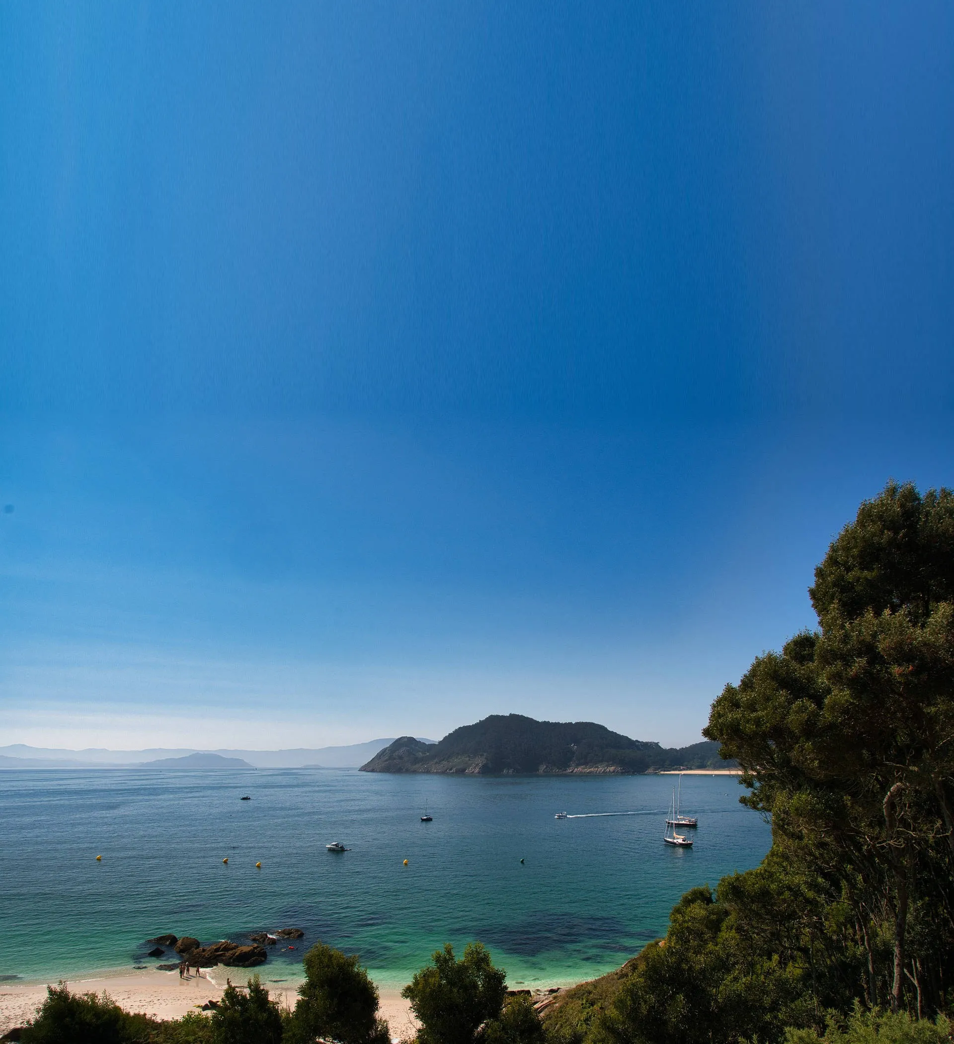 Galicische Bucht mit türkis-blauem Wasser mit Sicht auf Felsen und zwei ankernden Booten