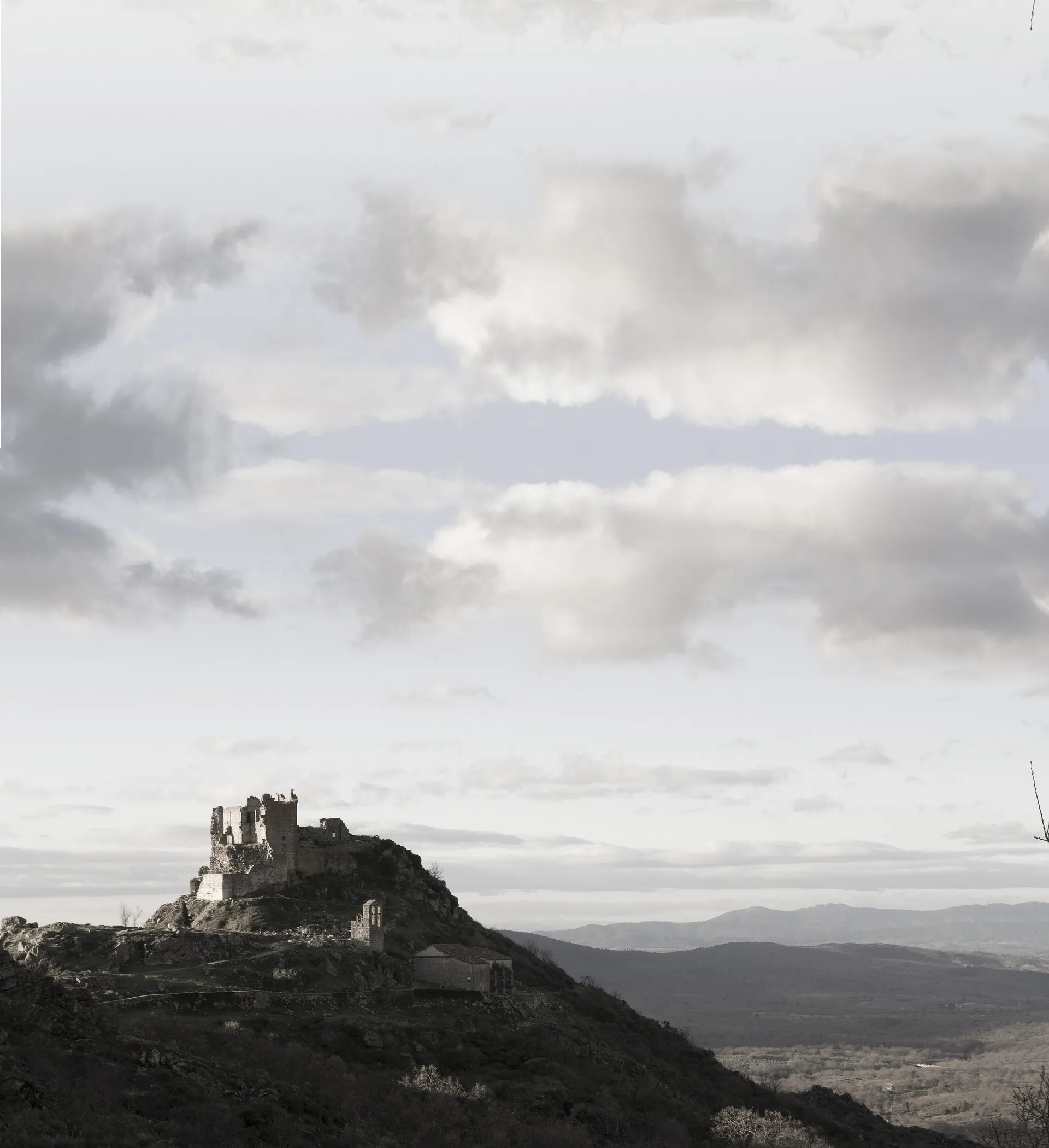 Schwarz/weiß-Bild einer Burgruine in Extremadura mit weiter Landschaft im Hintergrund